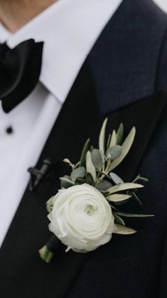 a man in a tuxedo wearing a boutonniere with white flowers