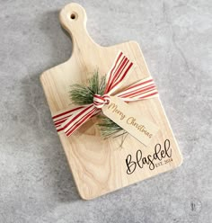 a wooden cutting board with a red and white striped ribbon tied around the handle that says happy christmas