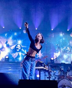 a woman standing on top of a stage with her arms in the air and holding a microphone