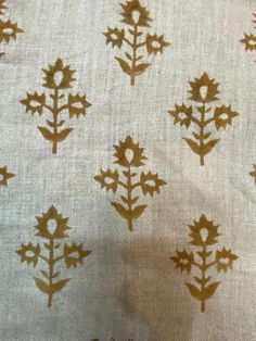 a white and gold fabric with brown leaves on the top, in an upclose pattern