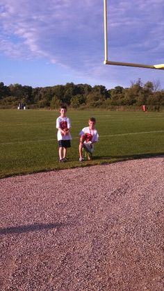 two young men sitting on the ground in front of a soccer goal