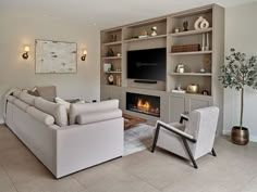 a living room filled with furniture and a flat screen tv mounted on a wall next to a fire place