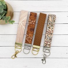 three key fobs are lined up next to a potted plant on a white wooden surface