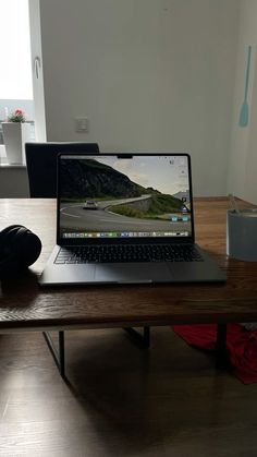 an open laptop computer sitting on top of a wooden table in front of a window