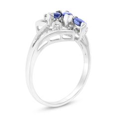 three stone ring in white gold with blue and white diamonds on the sides, set against a