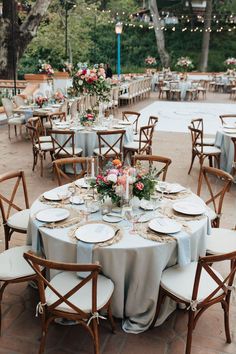 the tables are set with white plates and place settings for an outdoor dinner party or reception