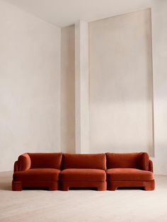 an orange couch sitting on top of a hard wood floor next to a white wall