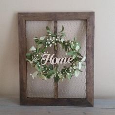 a wooden frame holding a wreath with the word home on it