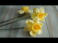 three crocheted yellow flowers sitting on top of a wooden table