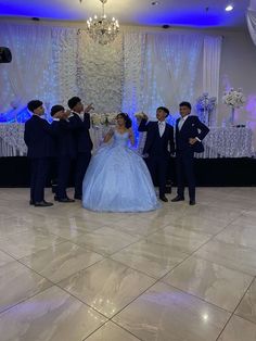 a group of people standing around each other in front of a chandelier with blue lights