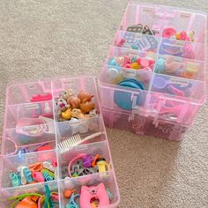 two plastic storage containers filled with toys on the floor in front of a carpeted area