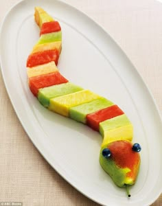 a white plate topped with fruit shaped like a caterpillar