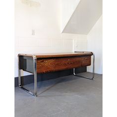 a wooden table sitting on top of a cement floor next to a white stair case