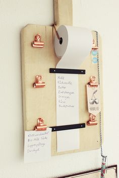 a bulletin board with some magnets on it and a roll of toilet paper hanging from the wall