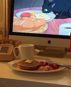 a breakfast plate with pancakes, bacon, and eggs on it in front of a computer screen