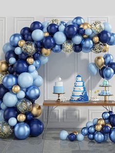 a blue and gold birthday party with balloons, cake and desserts on the table