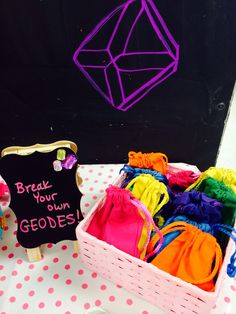 a pink basket filled with colorful clothes next to a chalkboard sign that says break your geodes