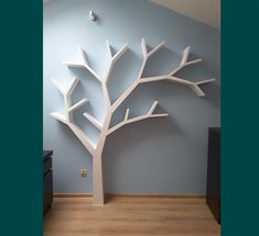 a white tree is in the corner of a room with blue walls and wood floors