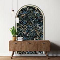 a room with a wooden cabinet, plant and wallpaper on the wall next to it