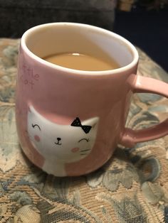 a pink coffee mug with a cat face on it