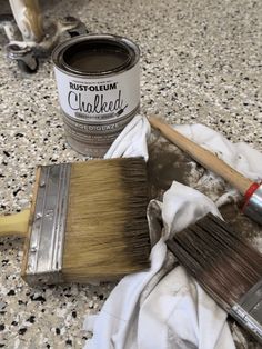 a paintbrush and brush sitting on top of a table next to a can of chalk