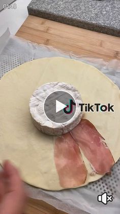 a person making food on top of a wooden cutting board with plastic wrap around it