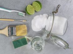 limes, toothbrushes and cleaning supplies laid out on a gray background with space for text