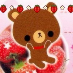 a brown teddy bear sitting on top of a strawberry covered cake