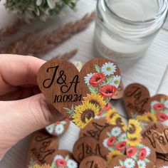 a person holding up a wooden heart shaped sticker with sunflowers on it