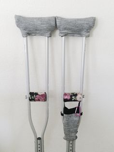 two metal crutches with flowers on them hanging from the side of a wall