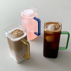 three different types of cold drinks on a white table with one beverage in the middle