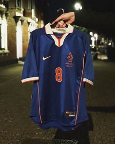 a person holding up a soccer jersey in the dark