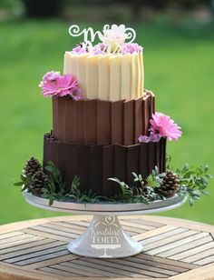 a three tiered chocolate cake with flowers on top