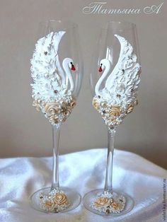 two wine glasses decorated with flowers and swans