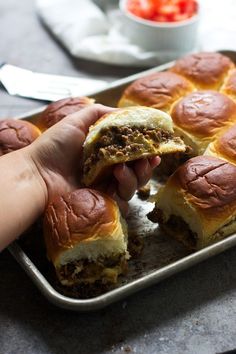 a person is taking a bite out of a meatball roll on a baking pan