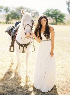 a woman standing next to a white horse