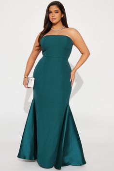 a woman in a long green dress with her hands on her hips, posing for the camera