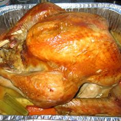 a roasting turkey in a foil pan with vegetables