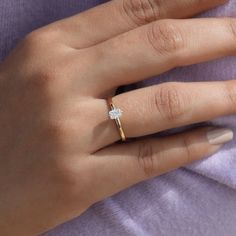 a woman's hand with a diamond ring on her left hand, wearing a purple shirt