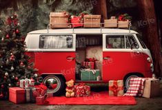 a red and white van with presents on the floor next to a christmas tree in front of it