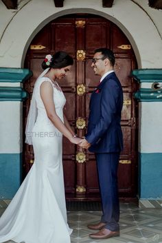 a bride and groom hold hands in front of a door at their wedding ceremony,