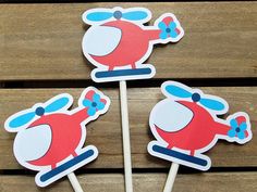 three red and blue cupcake toppers sitting on wooden sticks with stickers in the shape of a helicopter