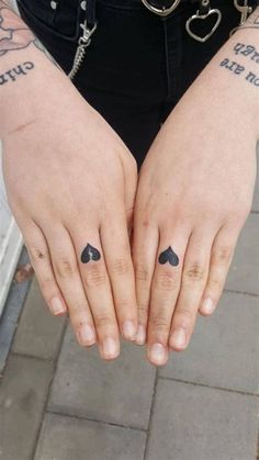 a person with tattoos on their hands holding onto each other's thumb and fingers