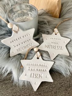 three white ceramic stars with names on them next to a glass cup and wooden block