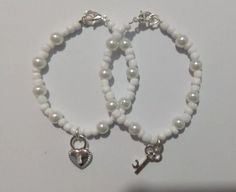 two white bracelets with charms on them