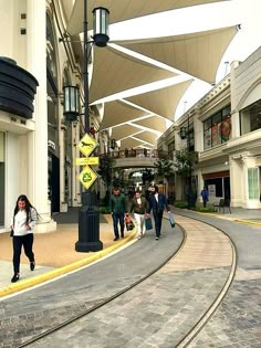 several people are walking down the street in an area with many shops and stores on either side