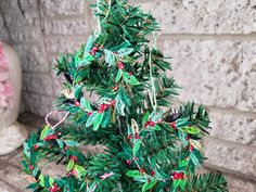 a small green christmas tree sitting on top of a wooden table next to a brick wall