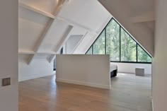 an empty room with wooden floors and large windows in the ceiling, along with white walls