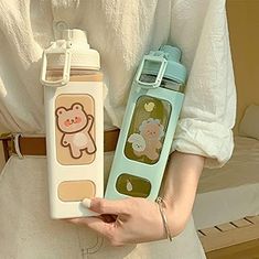 a woman is holding two water bottles in her hands, one with a bear design on it