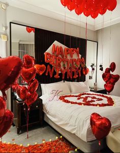 a bedroom decorated with red balloons and heart - shaped confetti on the bed